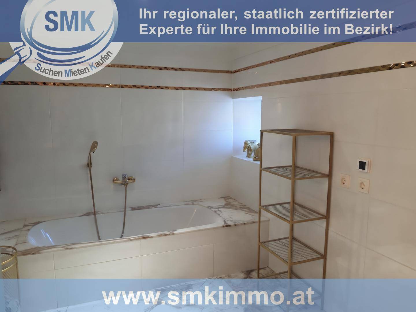 Helles Badezimmer mit Badewanne, weißen Fliesen und goldfarbenen Akzenten.