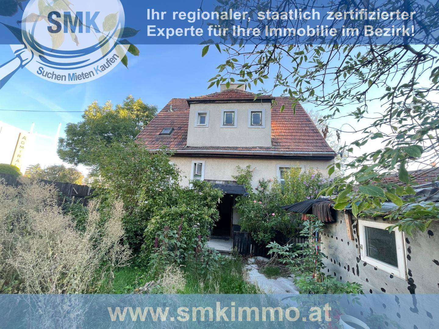 Rückseite des Hauses mit verwildertem Garten und kleinen Nebengebäuden, die Renovierung benötigen.
