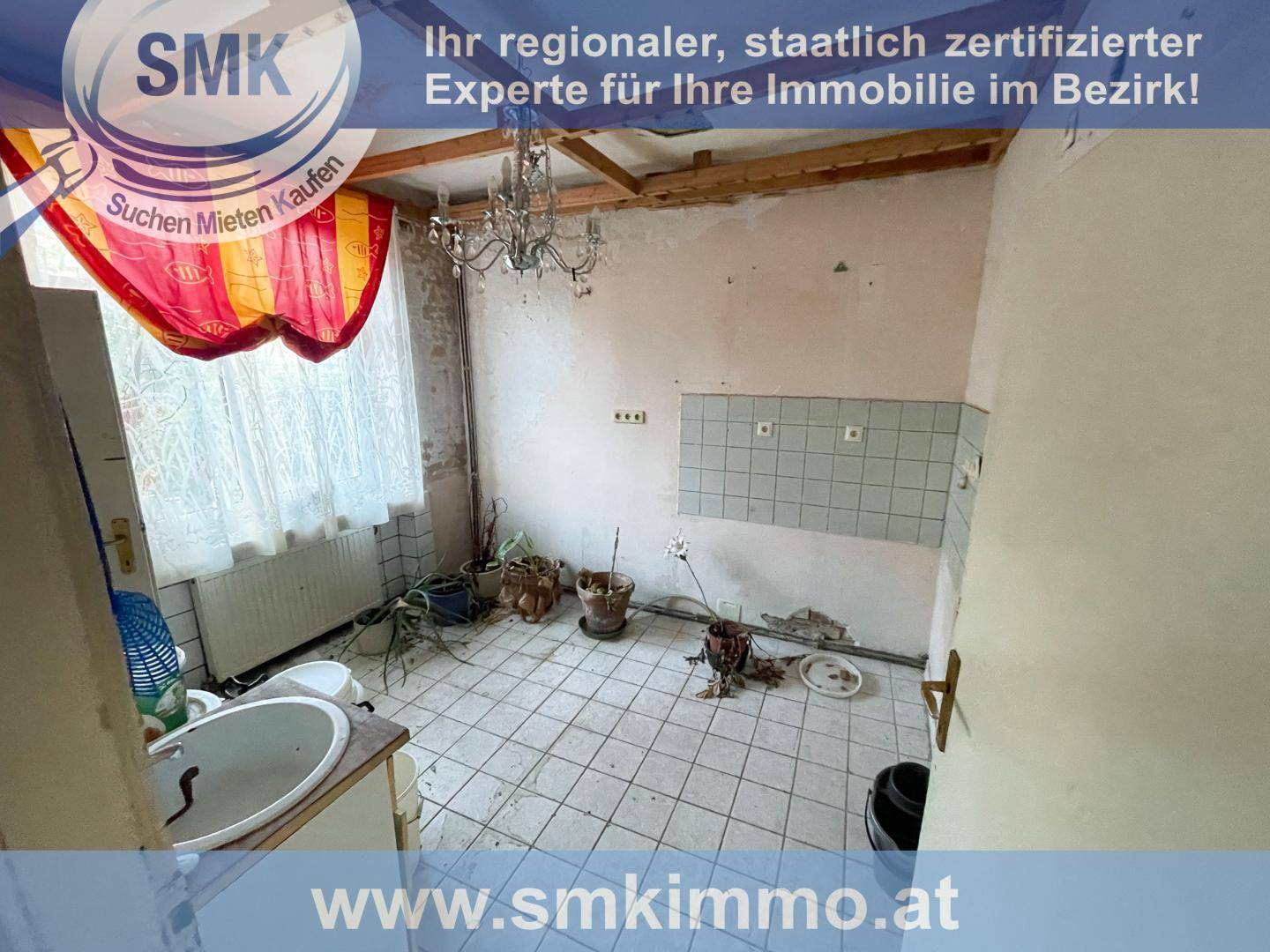 Alte Küche in schlechtem Zustand mit Fliesenboden, Spülbecken und sichtbaren Deckenbalken.