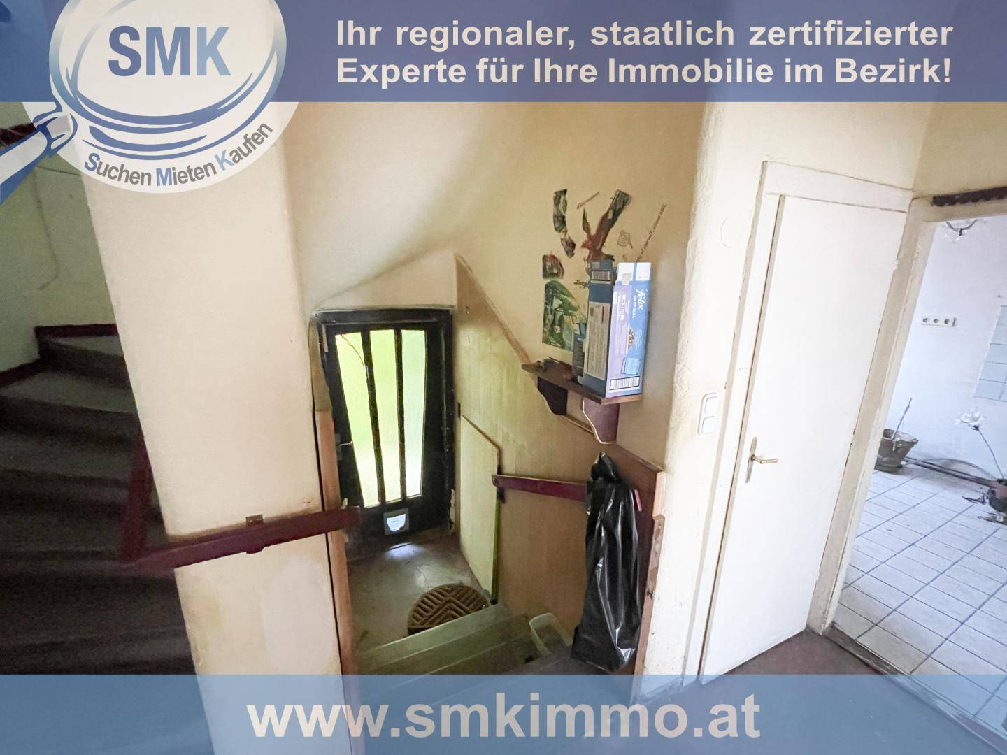 Weiterer Blick auf das abgenutzte Treppenhaus mit Eingangstür und sichtbaren Gebrauchsspuren.