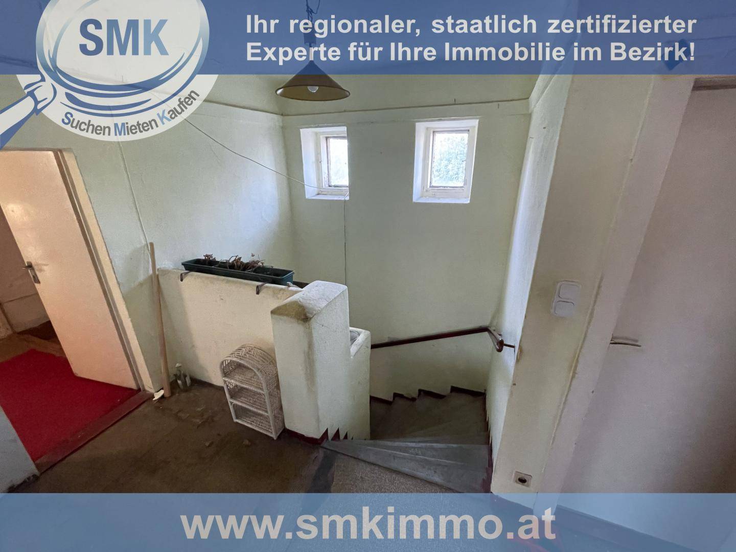 Altes Treppenhaus mit abgenutzten Stufen und kleinen Fenstern, das Renovierung benötigt.