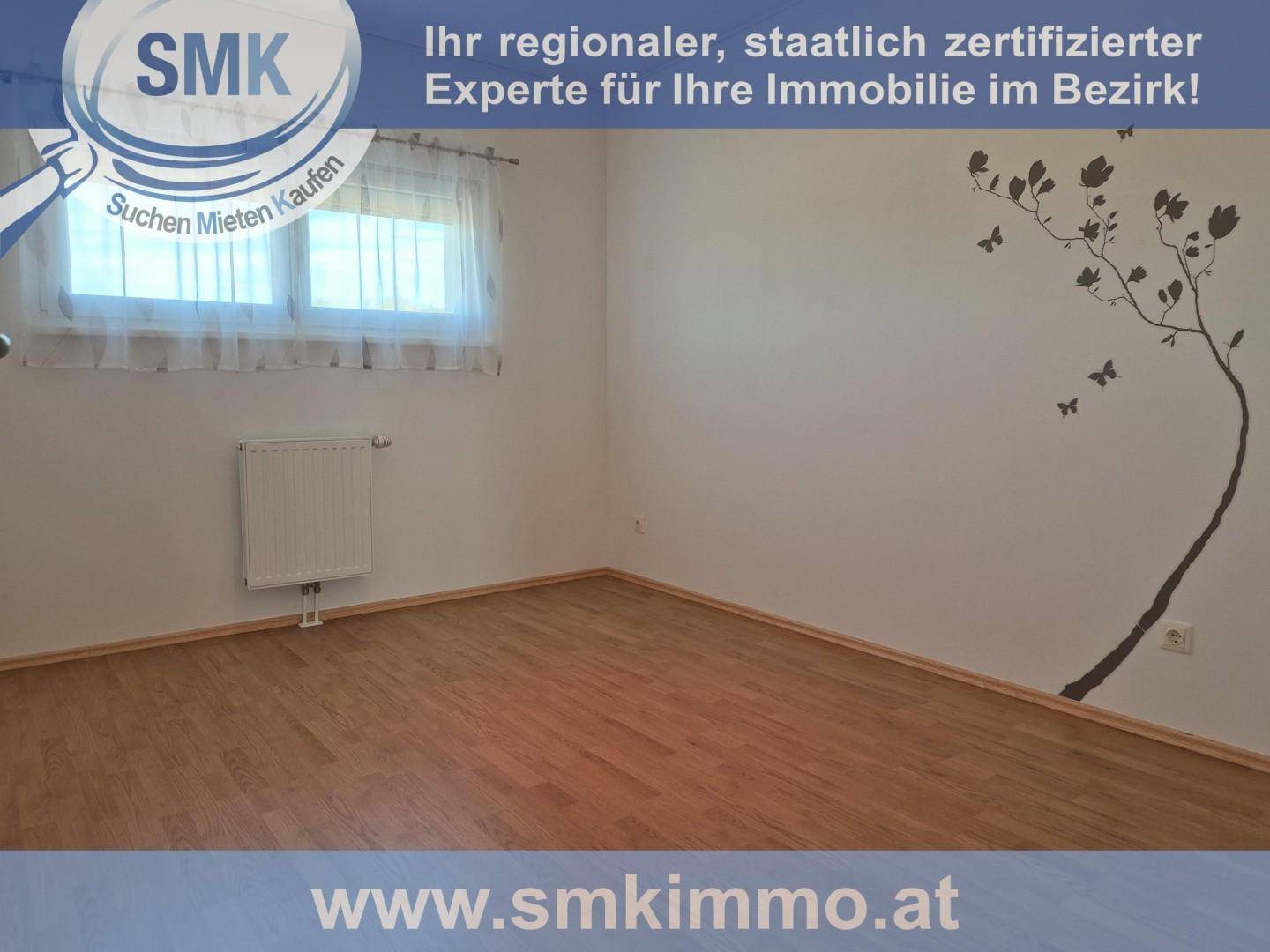 Gemütliches Zimmer mit Holzboden, Fenster und einem dekorativen Wandtattoo eines Baumes.