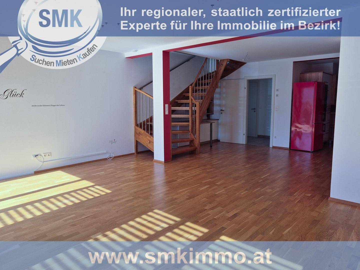 Geräumiges Wohnzimmer mit Holztreppe, Parkettboden und einem roten Kühlschrank im Hintergrund.