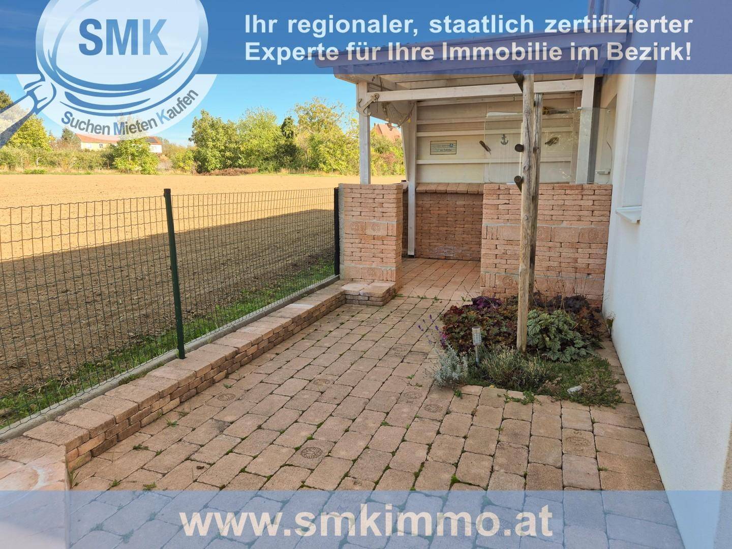 Gepflasterter Gartenbereich mit Ziegelmauern, einem kleinen Blumenbeet und einem Zaun.