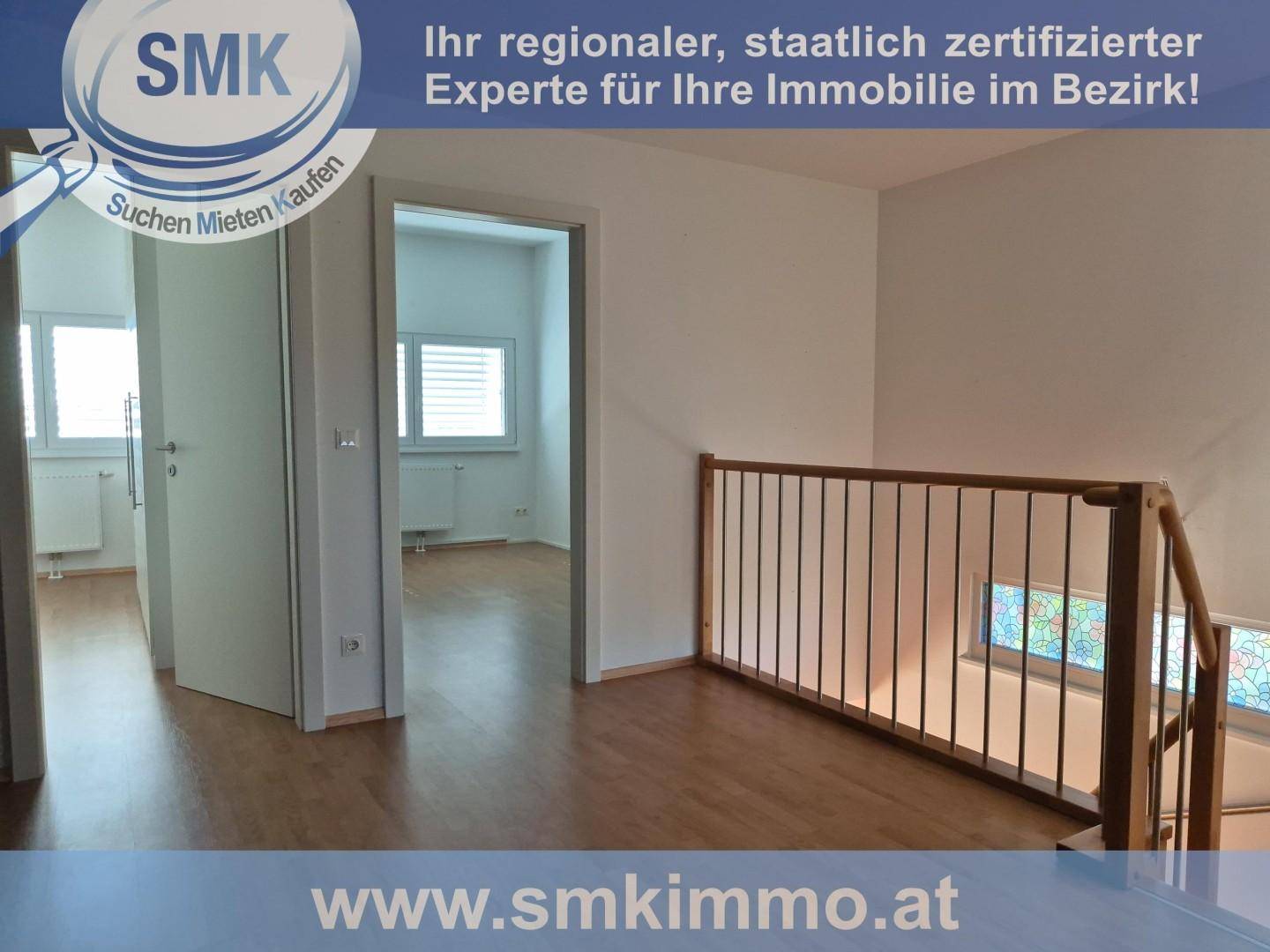 Heller Flur im Obergeschoss mit Holzboden und Blick auf den Treppenaufgang mit Buntglasfenstern.