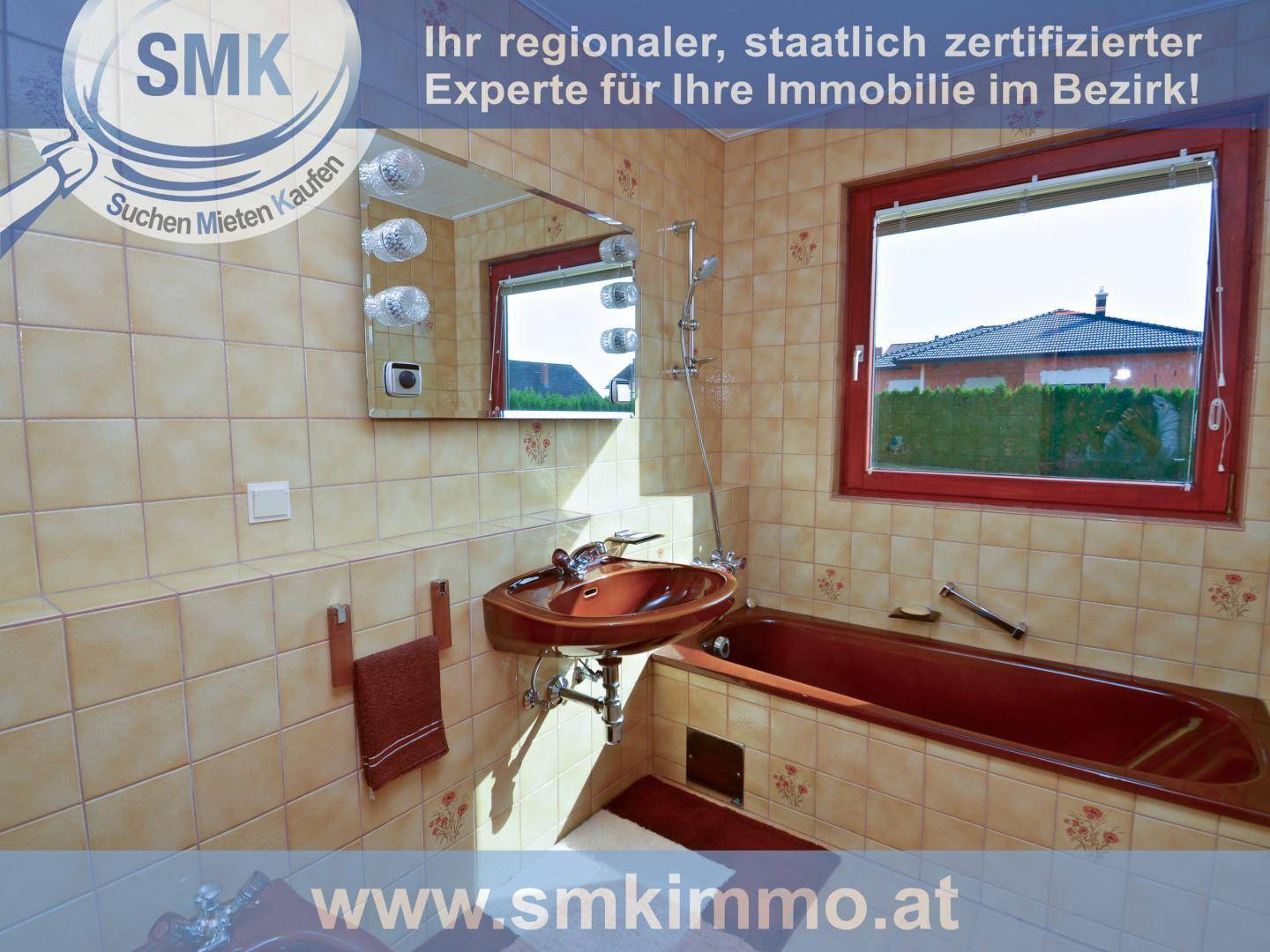 Badezimmer mit braunen Fliesen, passender Badewanne und Waschbecken sowie einem Fenster.