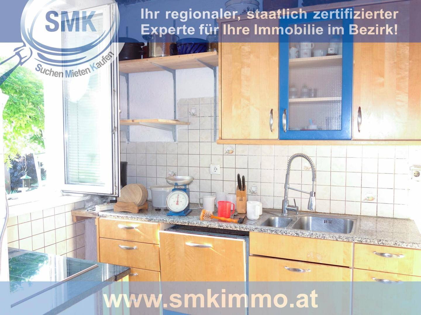 Küche mit Spüle, hellen Holzschränken, blauen Akzenten und einem Fenster.