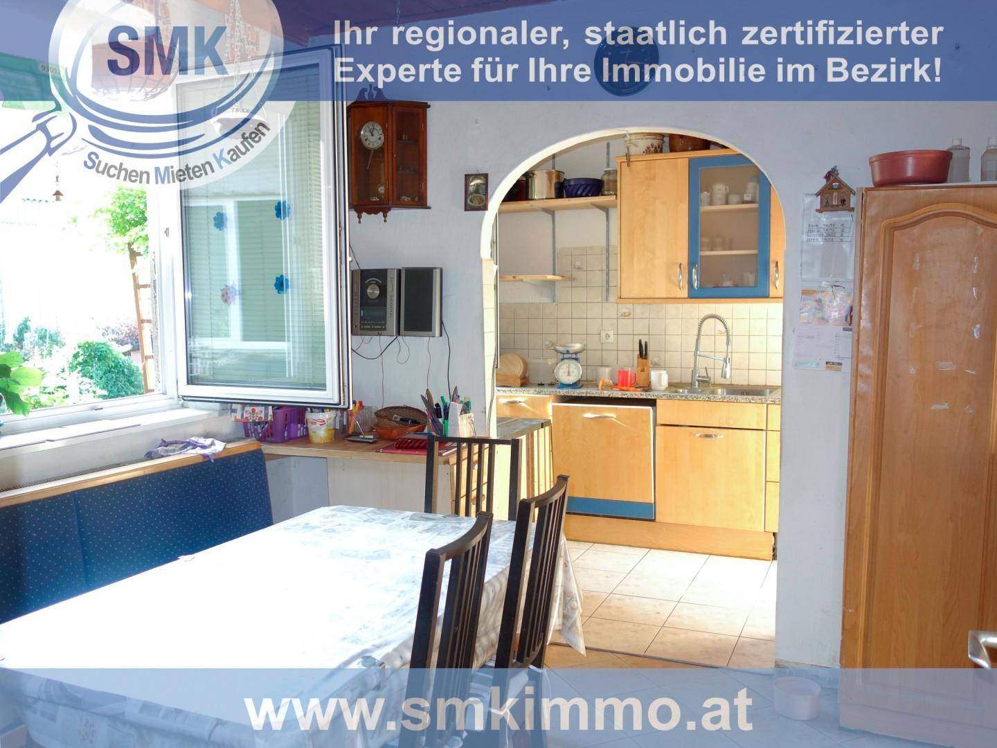 Essbereich mit Tisch und Sitzbank, angrenzend an eine Küche durch einen Rundbogen.