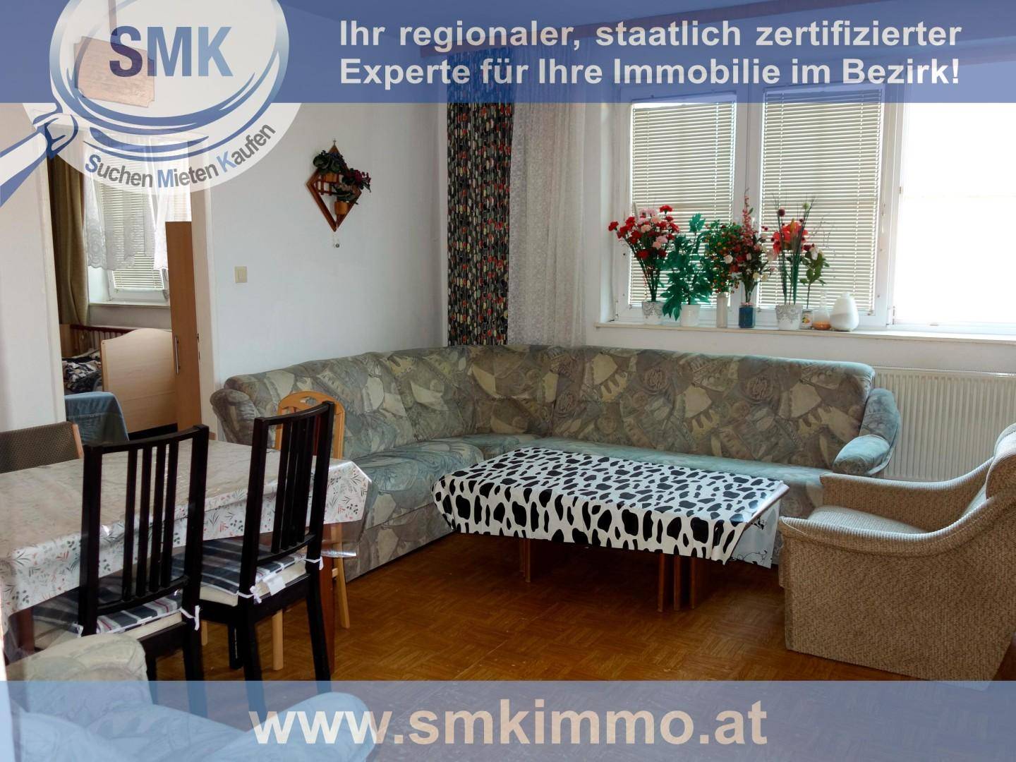 Wohn- und Essbereich mit Ecksofa, Esstisch und großem Fenster mit Blick nach draußen.