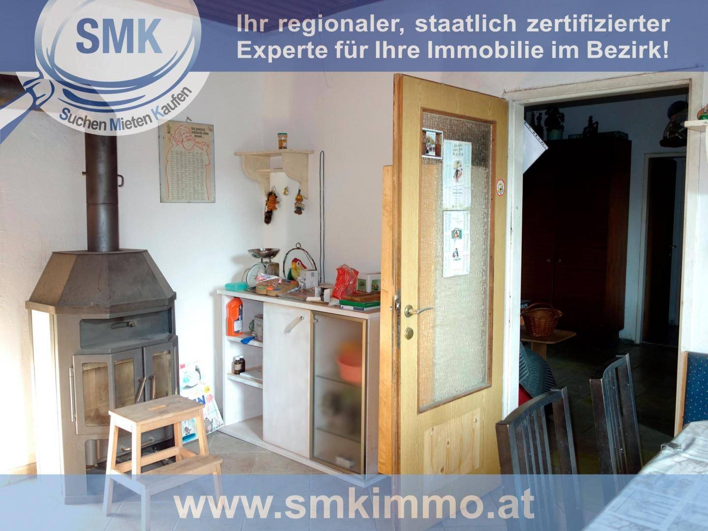 Raum mit einem Holzofen, einem kleinen Schrank und einer Holztür.