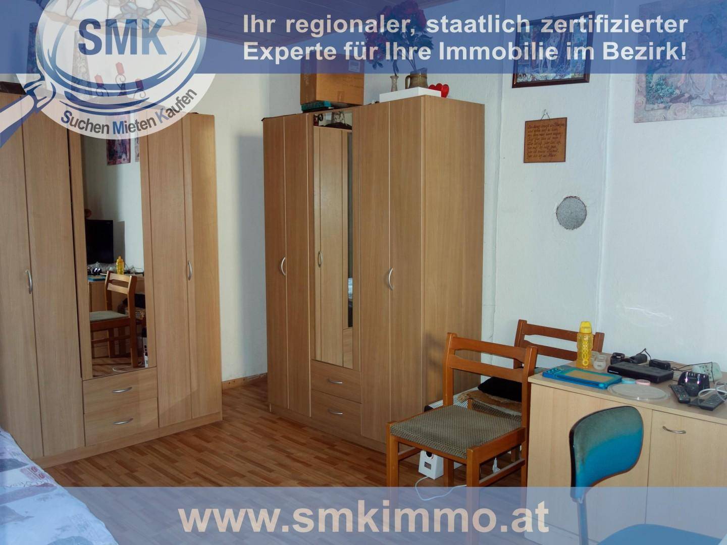 Schlafzimmer mit mehreren Holzschränken, einem Schreibtisch und Laminatboden.