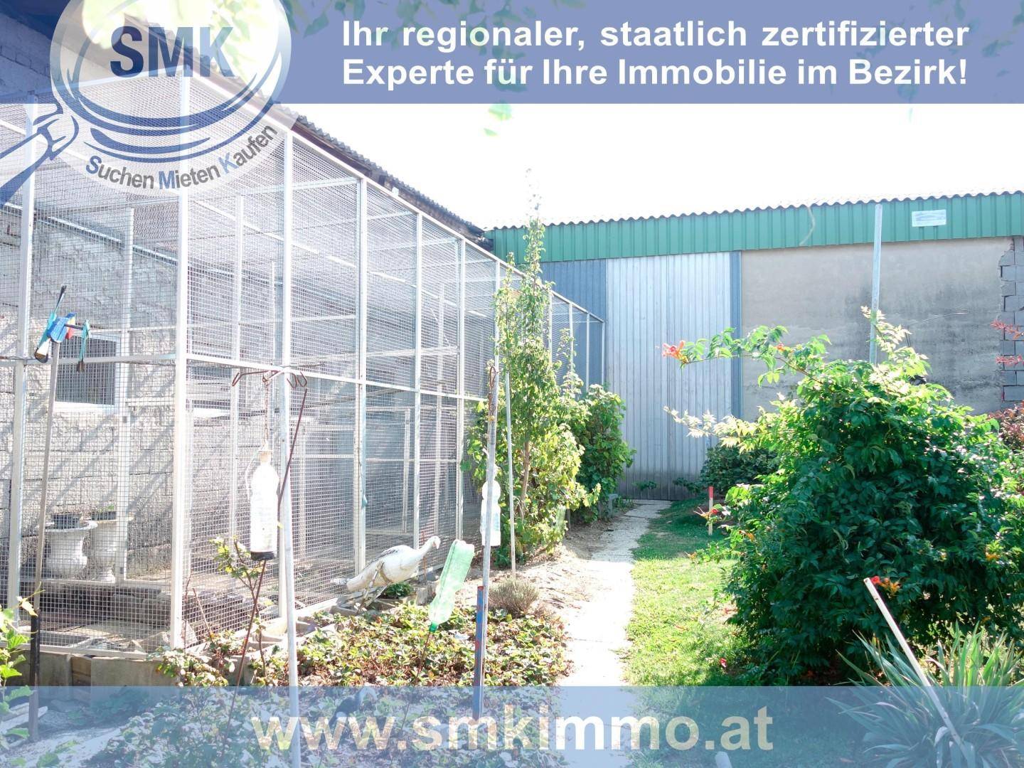 Gartenansicht mit großen Vogelvolieren, einem Pfad und vielfältiger Bepflanzung.