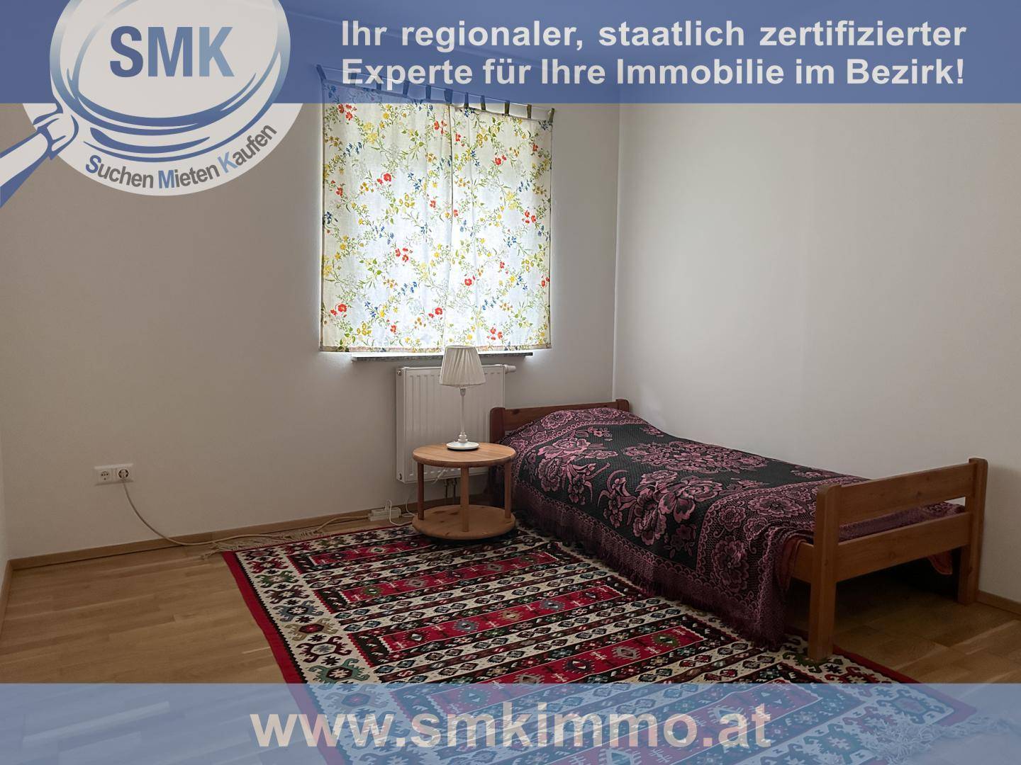 Helles Schlafzimmer mit Einzelbett, Holzboden und Fenster mit bunten Vorhängen.