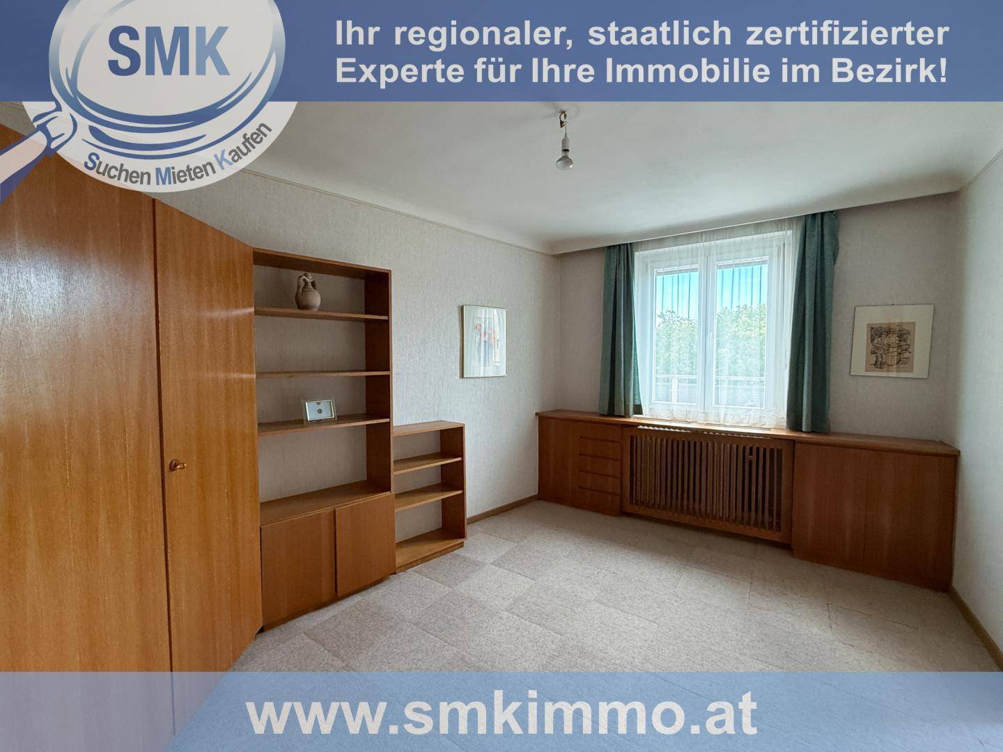 Geräumiges Zimmer mit großem Holzschrank, Regal und Fenster, das viel Tageslicht hereinlässt.