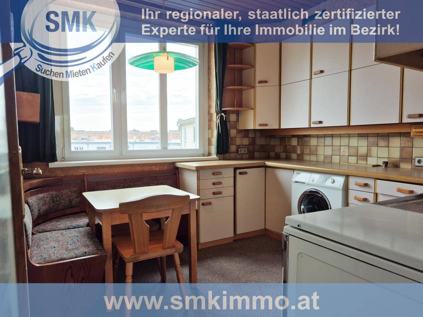 Funktionale Küche mit Essbereich, weißen Schränken und Fenster, das Tageslicht spendet.