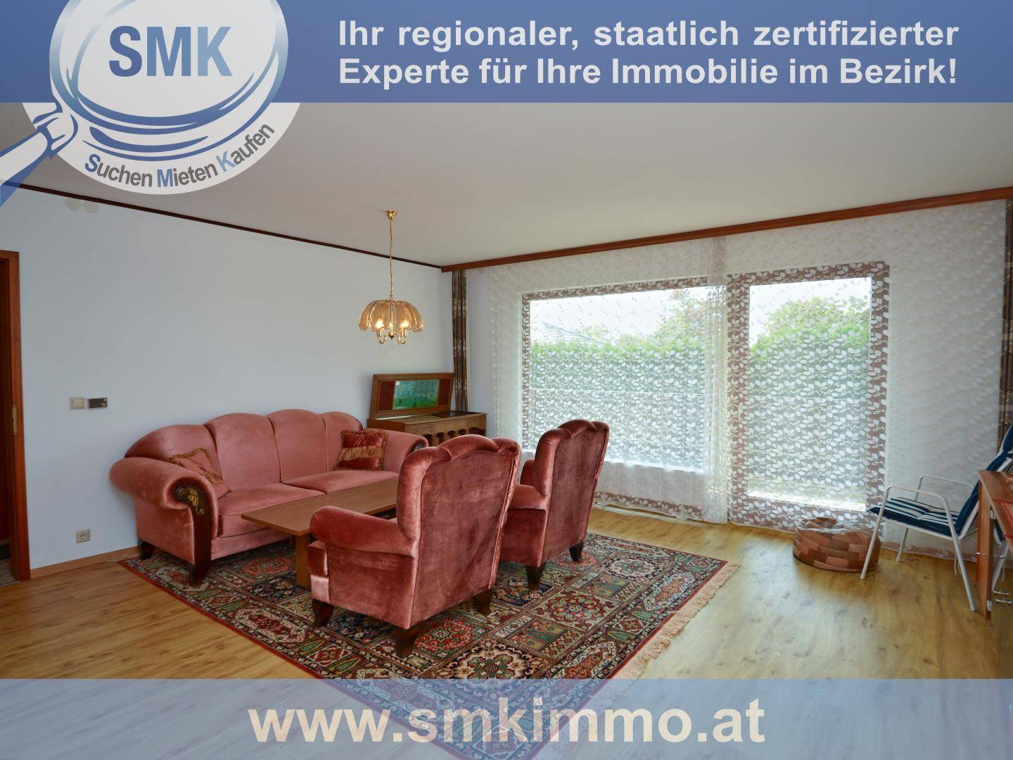 Wohnzimmer mit bequemen Samtsesseln, Teppich und großen Fenstern mit Blick ins Grüne.
