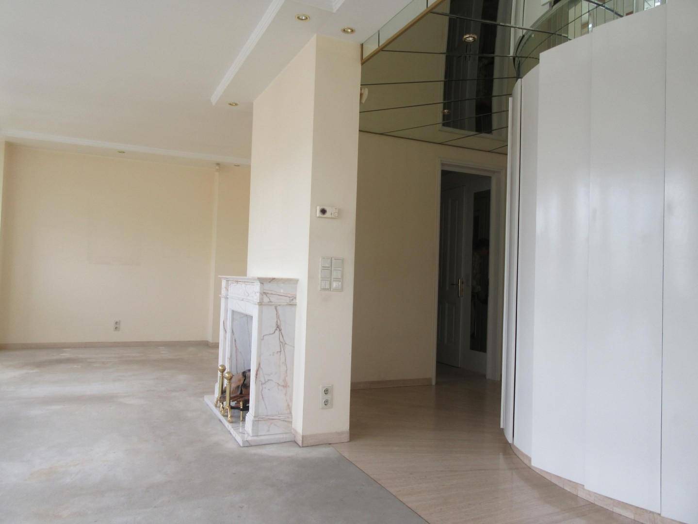 Geräumiges Wohnzimmer mit elegantem Marmorkamin und einer dekorativen Spiegelfliesendecke.