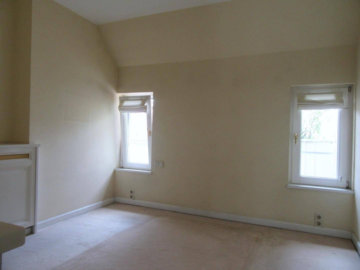 Helles Schlafzimmer mit Teppichboden und zwei Fenstern, bereit zur individuellen Gestaltung.