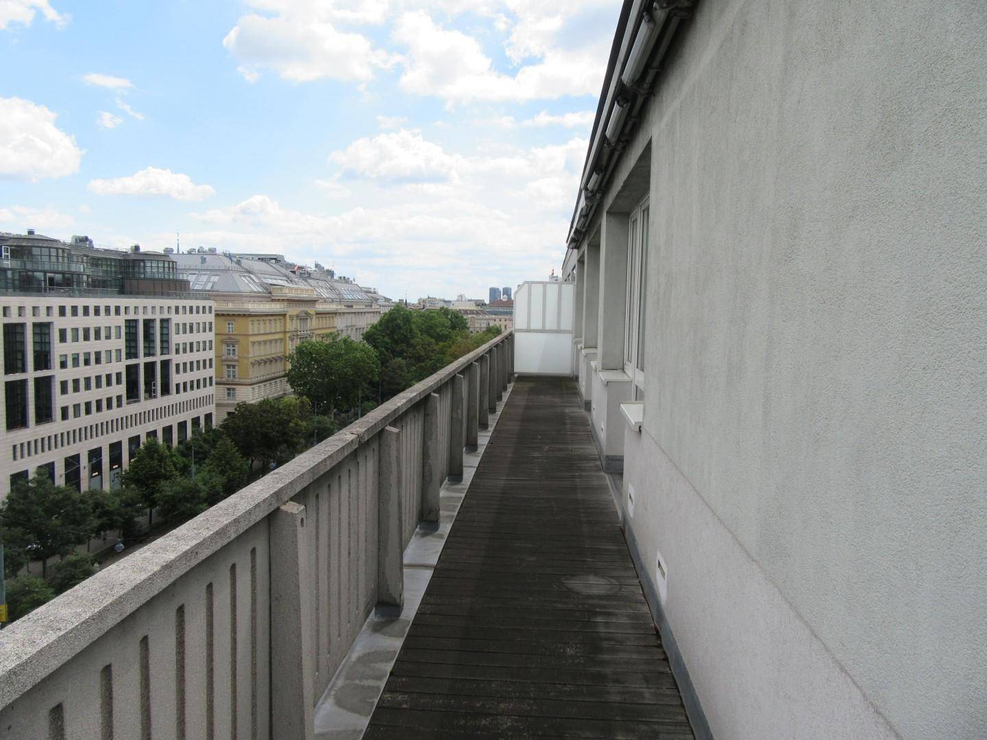 Langer Balkon mit Holzboden und weitem Blick über die städtische Umgebung.
