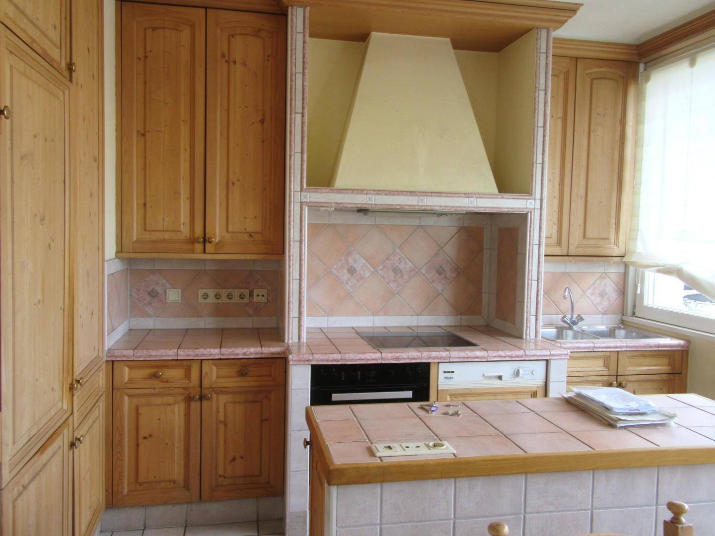 Traditionelle Küche mit Holzschränken, gefliestem Arbeitsbereich und integrierten Geräten.