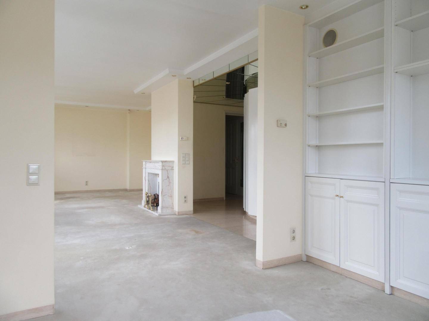 Geräumiges Wohnzimmer mit Marmorkamin, weißen Einbauregalen und heller Atmosphäre.