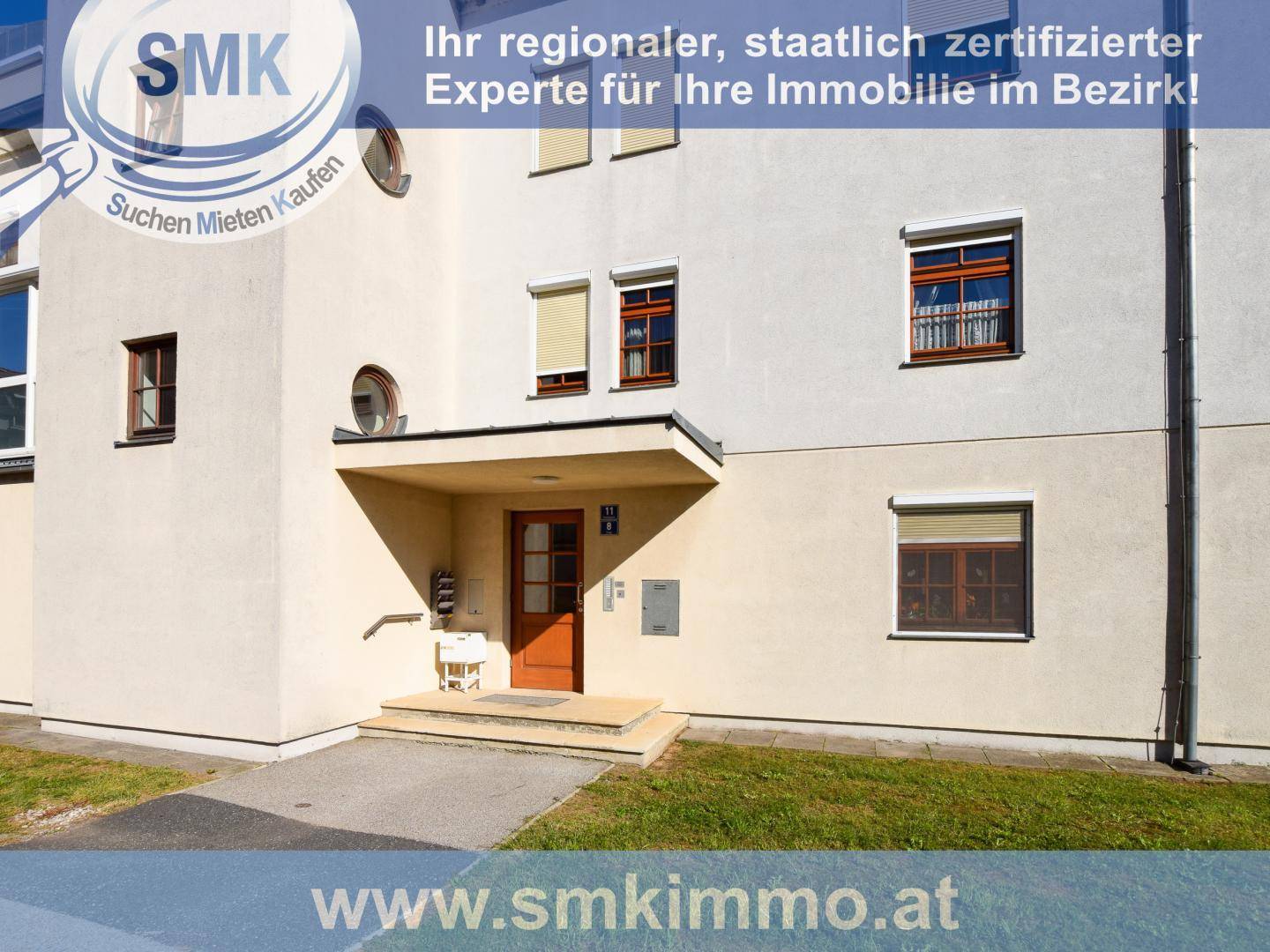 Mehrstöckiges Wohngebäude mit heller Fassade, verschiedenen Fenstern und einem Eingangsbereich.