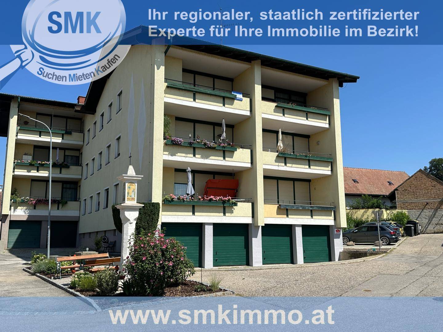 Mehrfamilienhaus mit mehreren Balkonen und Garagen im Erdgeschoss.