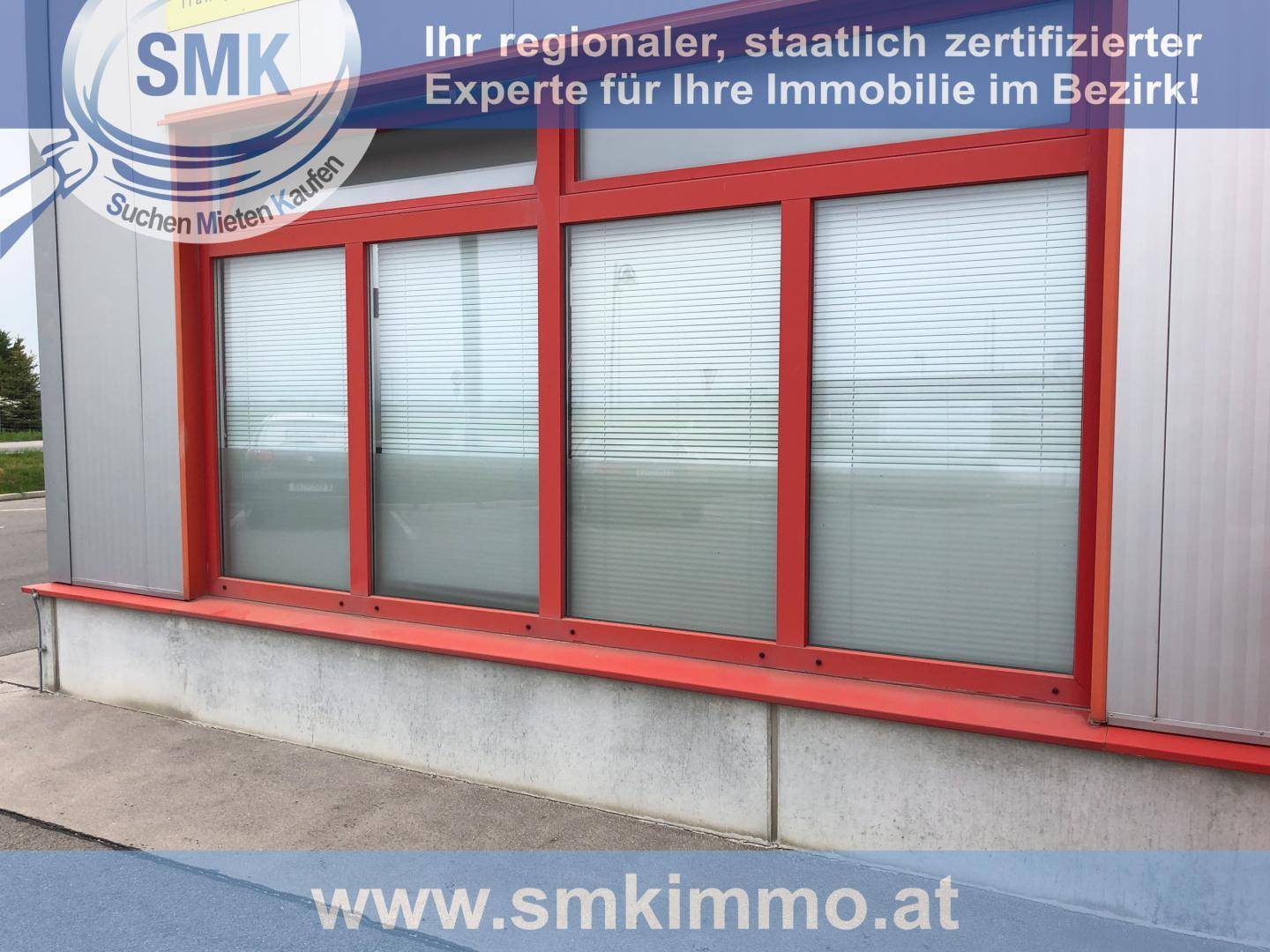 Detailansicht der roten Fensterfront eines modernen Geschäftsgebäudes mit Jalousien und einem Betonsockel.
