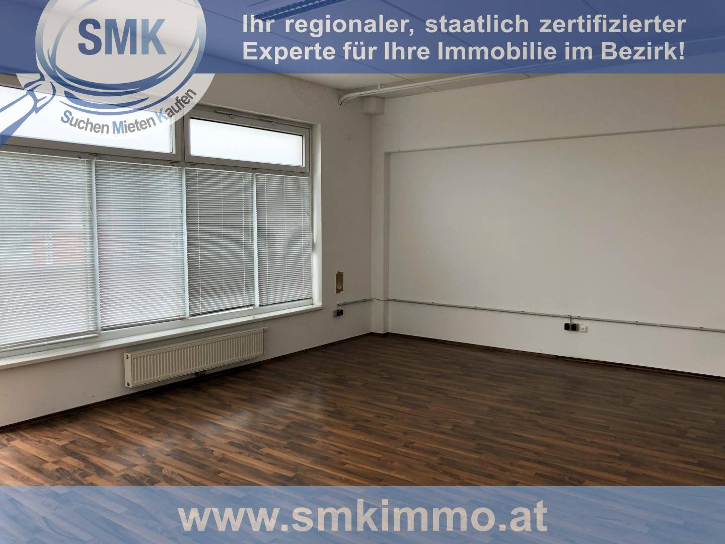 Geräumiger, leerer Innenraum mit weißen Wänden und dunklem Laminatboden, ideal für gewerbliche Nutzung.