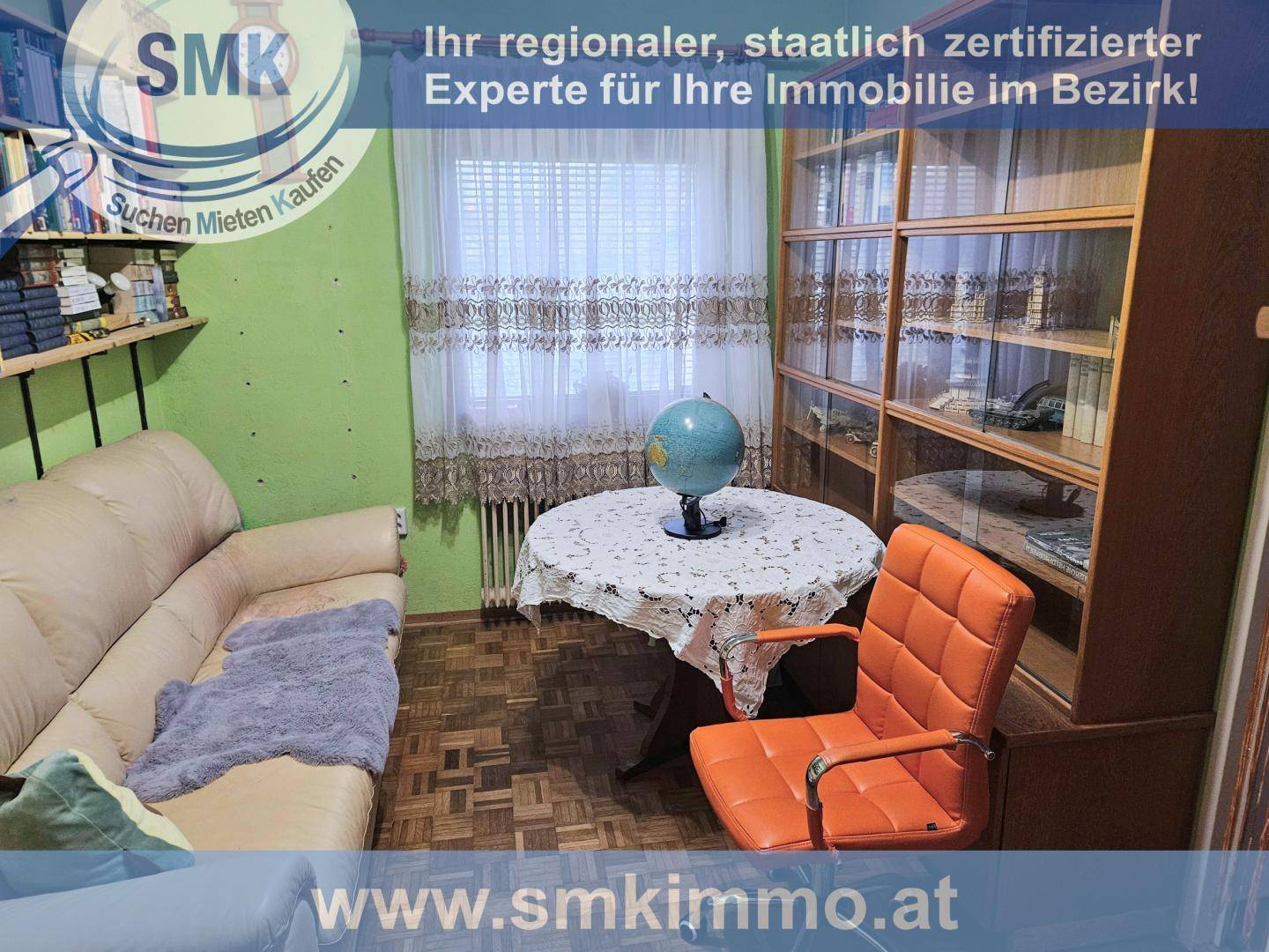 Wohnzimmer oder Arbeitsbereich mit Sofa, Bücherregal und kleinem Tisch.