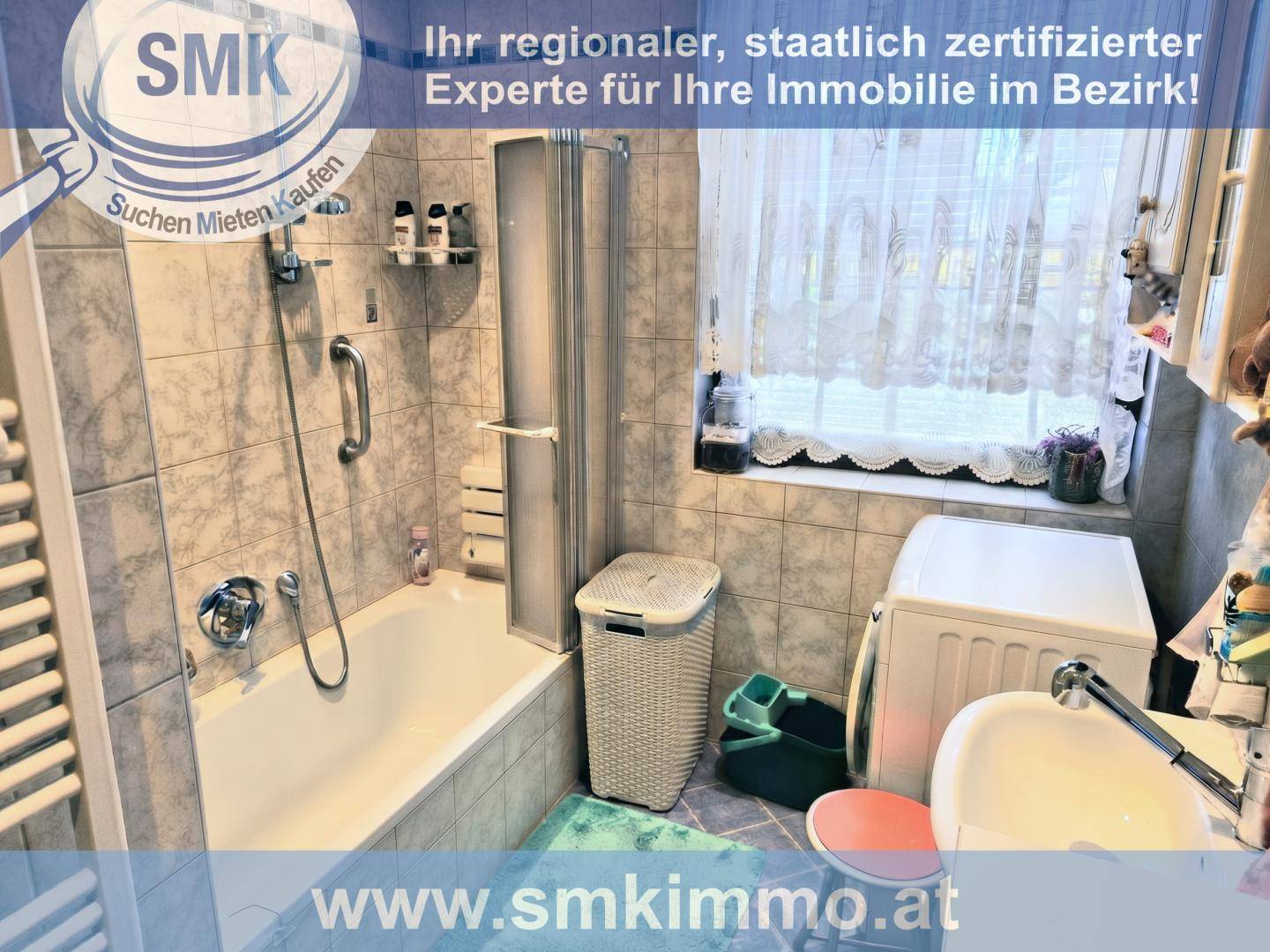 Badezimmer mit Badewanne, Duschabtrennung, Waschbecken und Waschmaschine.
