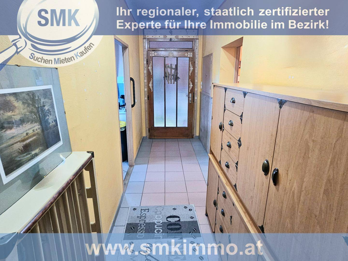 Heller Flur mit Fliesenboden, Holzschränken und Eingangstür mit Glaseinsatz.