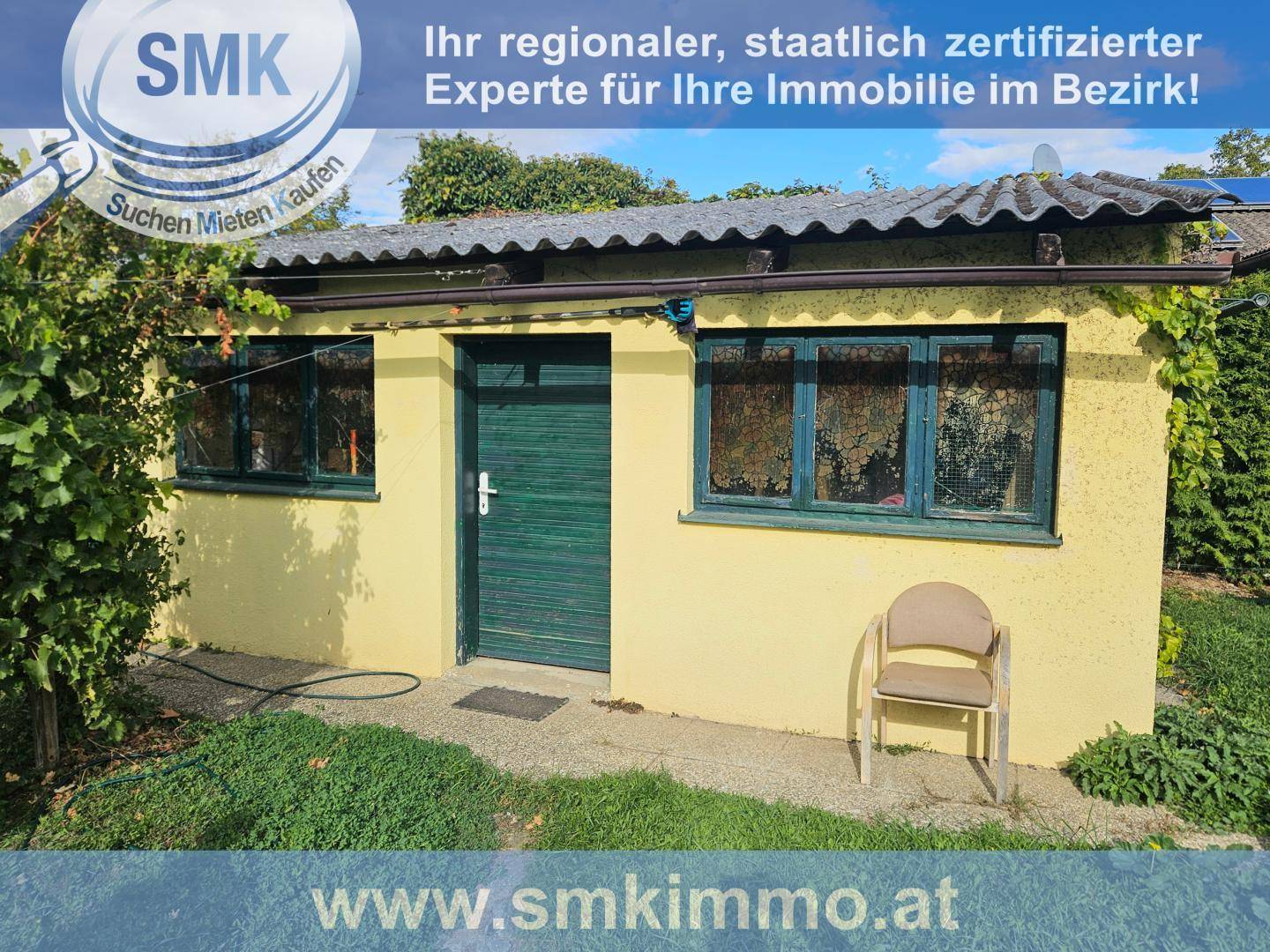 Kleines gelbes Gartenhaus mit grüner Tür und Fenstern im Grünen.
