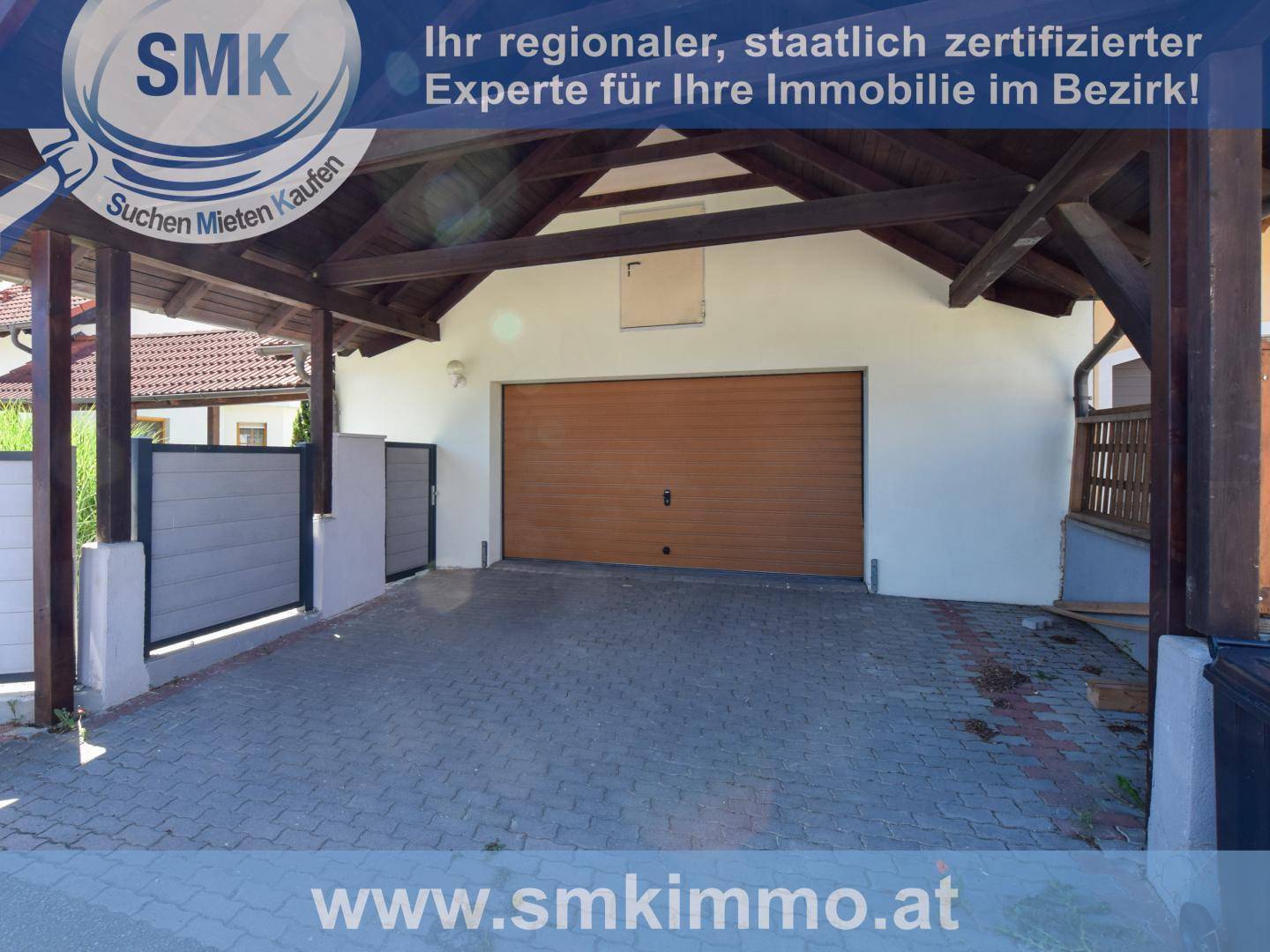 Geräumige Garage mit Holzrolltor und überdachtem Carport-Bereich davor.