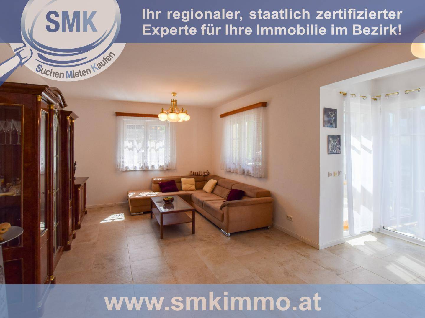 Gemütliches Wohnzimmer mit beigem Sofa, Holztisch und traditionellen Möbeln auf Fliesenboden.