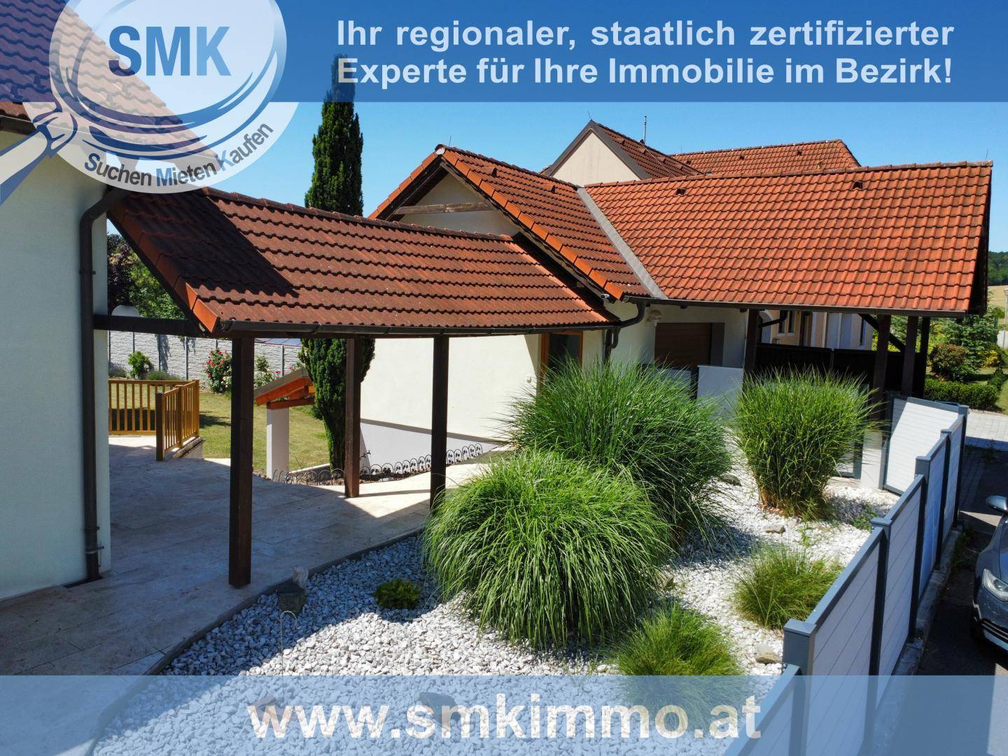 Seitenansicht des Hauses mit Carport, Ziergräsern und einem gepflegten Kiesbeet.