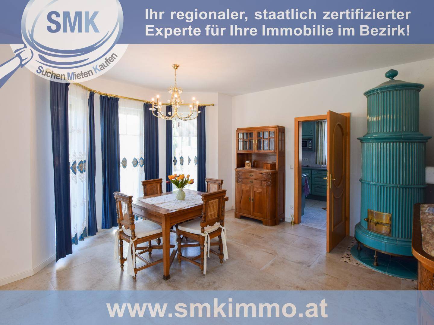 Traditioneller Essbereich mit Holztisch, Stühlen und einem markanten grünen Kachelofen.