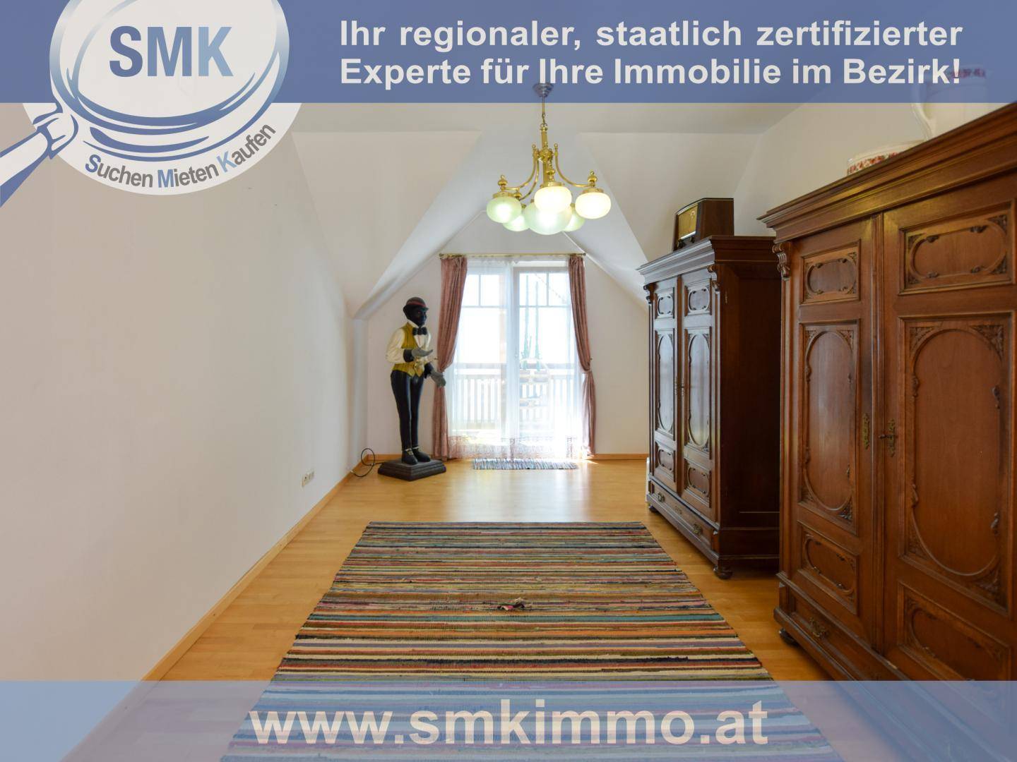 Schlafzimmer im Dachgeschoss mit Holzboden, Kleiderschränken und farbenfrohem Teppich.