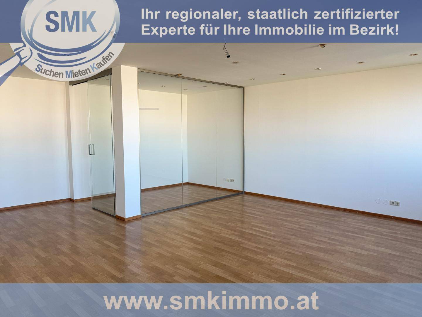 Geräumiger Innenraum mit hellem Holzfußboden und einer modernen Glasabtrennung.