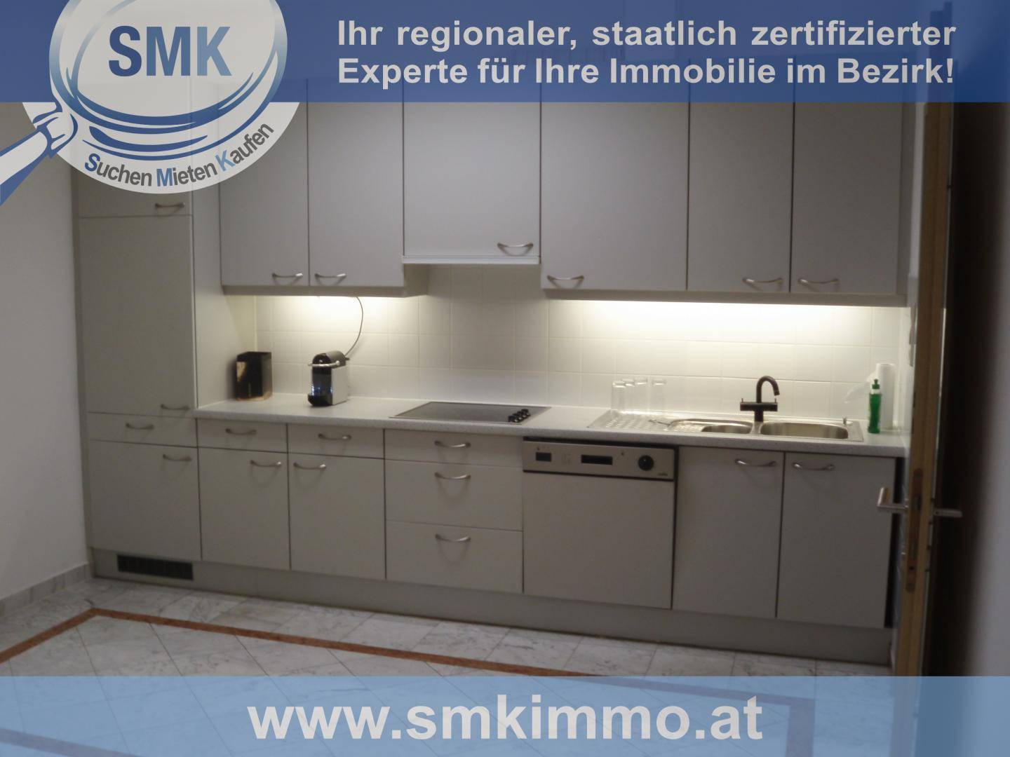 Moderne Küche mit grauen Schränken, integrierten Geräten und heller Arbeitsplatte.