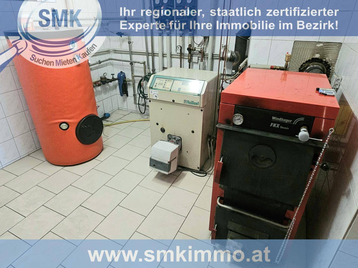 Heizungsraum mit Kessel, Warmwasserspeicher und technischen Installationen auf Fliesenboden.