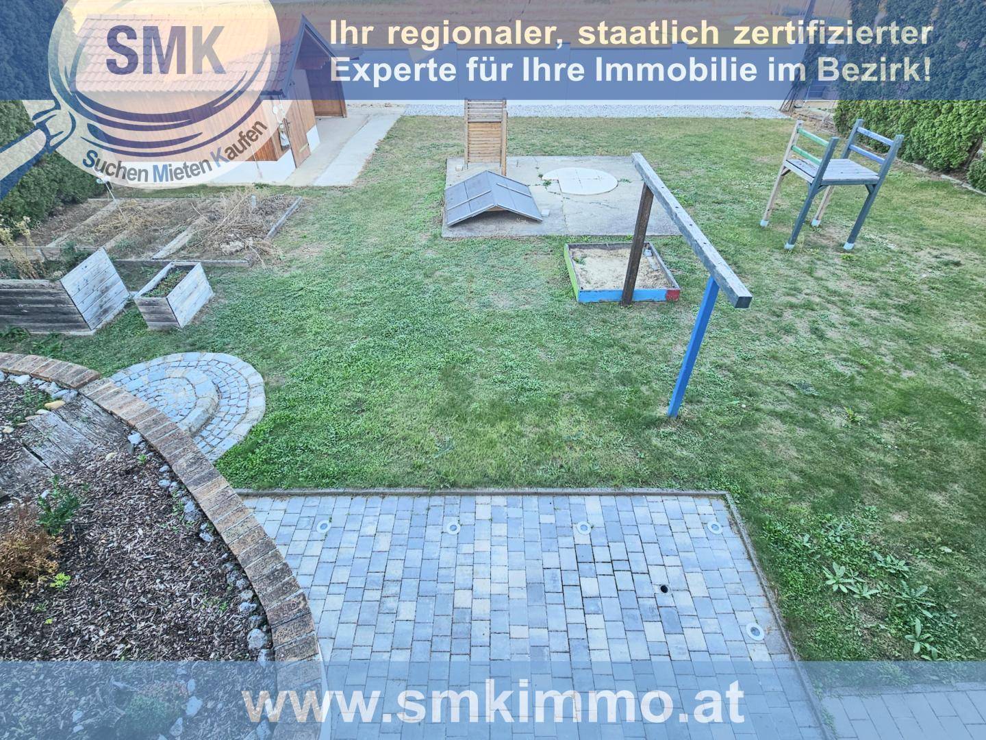 Großer Garten mit Rasenfläche, gepflastertem Bereich und Kinderspielgeräten.
