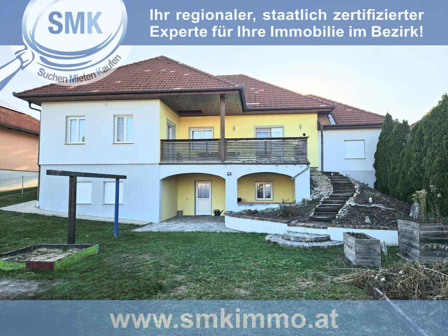 Rückansicht eines Hauses mit Garten, Terrasse und Treppe zum oberen Wohnbereich.