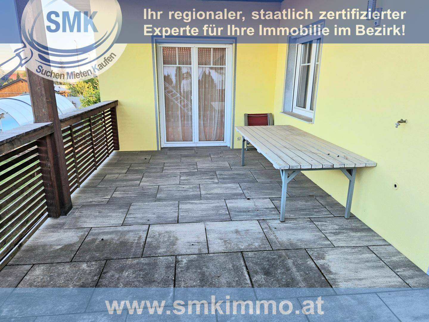 Gepflasterte Terrasse mit Holztisch und Geländer, ideal für Mahlzeiten im Freien.