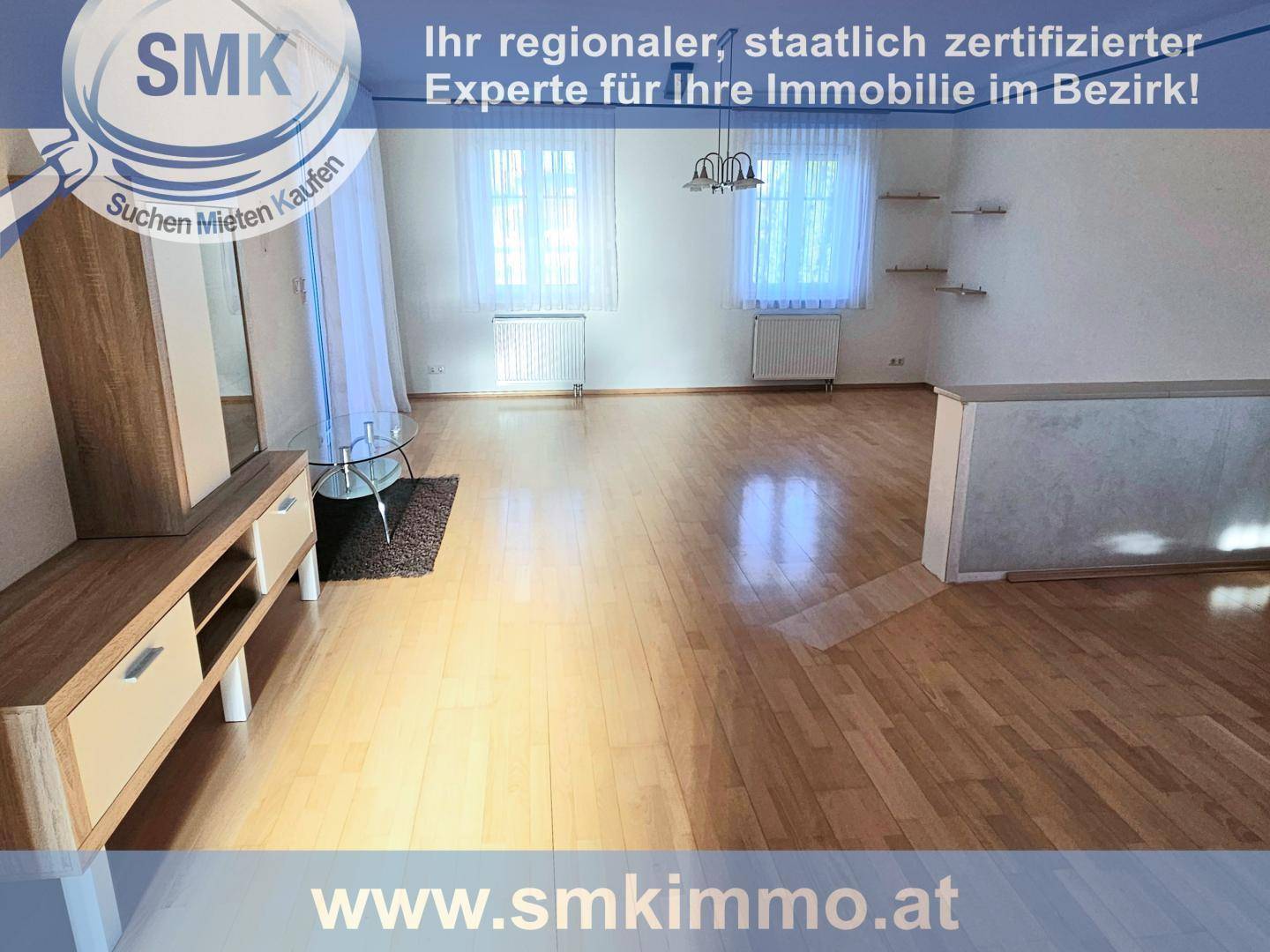 Heller Wohnbereich mit Parkettboden, großen Fenstern und einem modernen Sideboard.