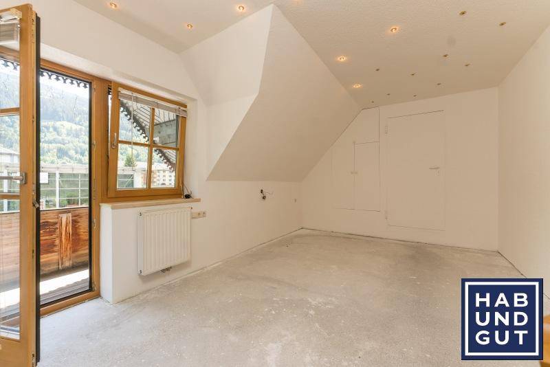 Leeres Zimmer im Dachgeschoss mit Balkonzugang und Einbaustrahlern an der Decke.