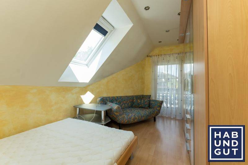 Schlafzimmer im Dachgeschoss mit Dachfenster, Schrägen und Zugang zum Balkon.