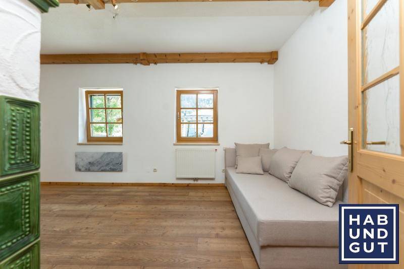 Gemütliches Wohnzimmer mit Holzbalken, Parkettboden und einer langen Sitzbank.
