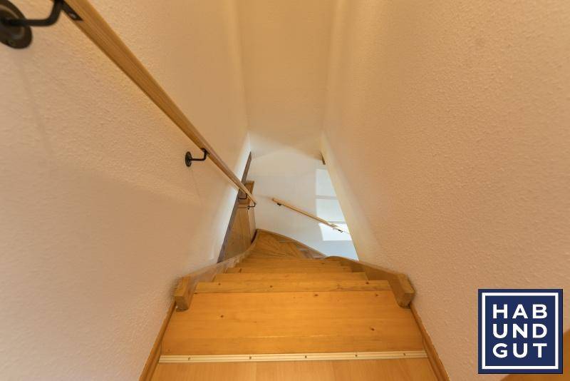 Holztreppe mit Handlauf, die in die obere Etage des Hauses führt.