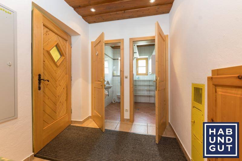 Heller Flur mit Holztüren, Fliesenboden und Zugang zu weiteren Räumen.